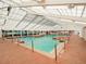 An indoor pool illuminated by a translucent ceiling is surrounded by a red-tiled deck with lounge chairs at 27003 Racquet Cir, Leesburg, FL 34748