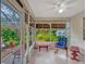 Bright sunroom featuring tile flooring, ceiling fan, and large windows with views of the landscaped backyard at 27003 Racquet Cir, Leesburg, FL 34748