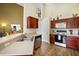 Well-lit kitchen with a stainless steel sink, modern appliances, wood cabinets and wood laminate floors at 2903 Blooming Alamanda Loop, Kissimmee, FL 34747