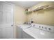 Laundry room with white washer and dryer, white storage shelves, and a white door at 2903 Blooming Alamanda Loop, Kissimmee, FL 34747