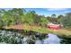 Breathtaking aerial view of a red barn with a metal roof next to a picturesque lake and trees at 31241 Benton Dr, Eustis, FL 32736