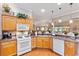 Efficient kitchen with wooden cabinetry, white appliances, and open view to dining area at 3163 Southern Trce, The Villages, FL 32162