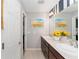 Bathroom featuring double sinks, wood cabinets, and a large mirror reflecting a sunflower picture at 3564 Nomad Ter, The Villages, FL 32163