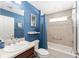 Well-lit bathroom featuring blue accent wall, tub-shower combo and modern fixtures at 3564 Nomad Ter, The Villages, FL 32163