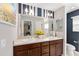 Bathroom with double vanity, wooden cabinets, blue and white striped accent wall, and a large mirror at 3564 Nomad Ter, The Villages, FL 32163