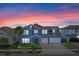 Two-story blue home showcasing a well-manicured lawn, a two-car garage, and beautiful landscaping at 481 Blue Cypress Dr, Groveland, FL 34736