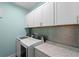 Laundry room with white cabinets, stainless steel washing machine and dryer, and a tiled backsplash at 481 Blue Cypress Dr, Groveland, FL 34736