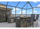 Outdoor kitchen with grill, bar seating, and stunning lake views through the screen enclosure at 481 Blue Cypress Dr, Groveland, FL 34736