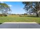 Backyard view with lush green grass and mature trees overlooking a greenbelt and golf course at 4826 Summerbridge Cir, Leesburg, FL 34748