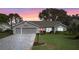 Inviting home featuring a red front door, a two-car garage, and a well-manicured lawn at sunset at 4826 Summerbridge Cir, Leesburg, FL 34748