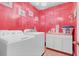 Laundry room with a bright pink wall, a washer and dryer set, and laundry organization at 4951 Cypress Hammock Dr, St Cloud, FL 34771