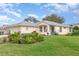 Well-maintained home exterior with lush landscaping, green lawn and blue front door under a sunny blue sky at 5370 Indian Ocean Loop, Tavares, FL 32778