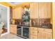 Kitchen wet bar featuring wooden cabinets, granite countertop, tile backsplash, mirrored shelf, and a beverage refrigerator at 5370 Indian Ocean Loop, Tavares, FL 32778