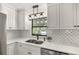 Close-up of a modern kitchen featuring white cabinets, stainless steel appliances, and stylish backsplash at 580 Page Ln, Mount Dora, FL 32757