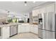 Kitchen featuring stainless steel refrigerator, white cabinets, granite counters, and an open layout to the living area at 589 Sherwood St, The Villages, FL 32162