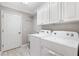 A laundry room with a white washer and dryer, white cabinets, and gray tile floors at 589 Sherwood St, The Villages, FL 32162