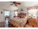 Bedroom featuring a ceiling fan, windows, bedside tables, wood floors, and patterned bedding at 5952 Brittania Blvd, Tavares, FL 32778