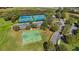 Aerial view of two tennis courts, a basketball court, and a playground near a pond in a landscaped community at 6240 Tremayne Dr, Mount Dora, FL 32757