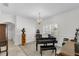 Charming living room showcasing a black grand piano, decorative lighting, and neutral carpeting at 6240 Tremayne Dr, Mount Dora, FL 32757