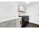 Bright laundry room features a white sink, countertop, overhead cabinets, and front-load washer and dryer at 674 Waterman Way, The Villages, FL 32163