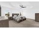 Spacious main bedroom featuring a ceiling fan, tray ceiling, and large windows at 674 Waterman Way, The Villages, FL 32163