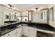 Bathroom features double sinks, black granite countertops, white cabinetry and large mirrors at 686 Aberdeen Run, The Villages, FL 32162