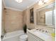 Bright bathroom with tub-shower combo, travertine tile, large mirror, and vanity sink at 686 Aberdeen Run, The Villages, FL 32162