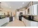 Open-concept kitchen with white cabinets, black appliances, and granite countertops seamlessly connecting to the dining and living areas at 686 Aberdeen Run, The Villages, FL 32162