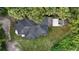 Birds-eye view of a newly renovated house with a dark roof, a small outbuilding, and mature trees all around at 709 S Highland St, Mount Dora, FL 32757