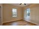 Light-filled bedroom with wood-look flooring, neutral walls, ceiling fan, and dual windows at 709 S Highland St, Mount Dora, FL 32757