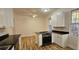 Eat-in kitchen features white cabinets, black countertops, stainless steel appliances, and modern light wood flooring at 709 S Highland St, Mount Dora, FL 32757