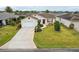 Aerial view of a well-landscaped home with a large driveway, manicured lawn, and charming curb appeal at 853 Abaco Path, The Villages, FL 32163