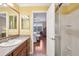 Bright bathroom with a wooden vanity, mirror, shower stall, and doorway view to the bedroom at 853 Abaco Path, The Villages, FL 32163