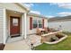 Charming front patio featuring cozy seating area with brick pavers, flowerbeds, and manicured lawn at 853 Abaco Path, The Villages, FL 32163