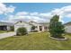 Lovely home with a green lawn, neat landscaping, and a welcoming front entrance with red door at 853 Abaco Path, The Villages, FL 32163