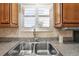 Close up of stainless steel kitchen sink and window with plantation shutters and wood cabinets at 853 Abaco Path, The Villages, FL 32163