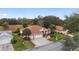 Aerial view of a well-maintained home featuring a manicured lawn, a paved driveway, and a two-car garage at 9894 Se 138Th Loop, Summerfield, FL 34491