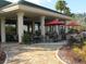 Outdoor seating area with tables, chairs, and umbrellas in a landscaped setting for relaxation and socializing at 9894 Se 138Th Loop, Summerfield, FL 34491