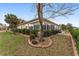 View of the sun room surrounded by a green lawn, shrubs, and a back patio at 9894 Se 138Th Loop, Summerfield, FL 34491