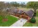 Aerial view of a brick home with a well-manicured lawn and a large driveway at 9906 County Road 114A, Wildwood, FL 34785