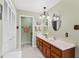 Bathroom featuring wood cabinets, double sinks, and an oval mirror at 9906 County Road 114A, Wildwood, FL 34785