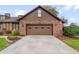 Two-car garage features a brick facade and modern door design, with an American flag at 9906 County Road 114A, Wildwood, FL 34785