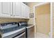 Modern laundry room with front-loading washer and dryer and ample storage in white cabinets at 9906 County Road 114A, Wildwood, FL 34785