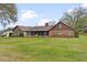 Rear view of home showcasing brickwork, screened porch, and expansive lawn at 9906 County Road 114A, Wildwood, FL 34785