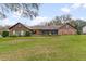 Back of house featuring brick exterior, screened-in porch, and lush green lawn at 9906 County Road 114A, Wildwood, FL 34785