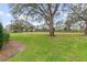 Large grassy yard with mature trees and a blue sky at 9906 County Road 114A, Wildwood, FL 34785