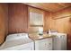 Functional laundry room showcasing wood paneled walls, a practical countertop, and essential washer and dryer units at 102 Palm Way, Tavares, FL 32778