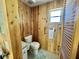 This bathroom features wood paneled walls, a window, and a standard toilet at 104 Chestnut St, Leesburg, FL 34748