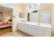 Well-lit bathroom with double sink vanity, tile floors, large mirror, and convenient access to bedroom at 12239 Se 92Nd Court Rd, Summerfield, FL 34491
