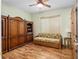 Inviting bedroom featuring hardwood floors, a ceiling fan, woven blind, and large wooden wardrobe at 12239 Se 92Nd Court Rd, Summerfield, FL 34491